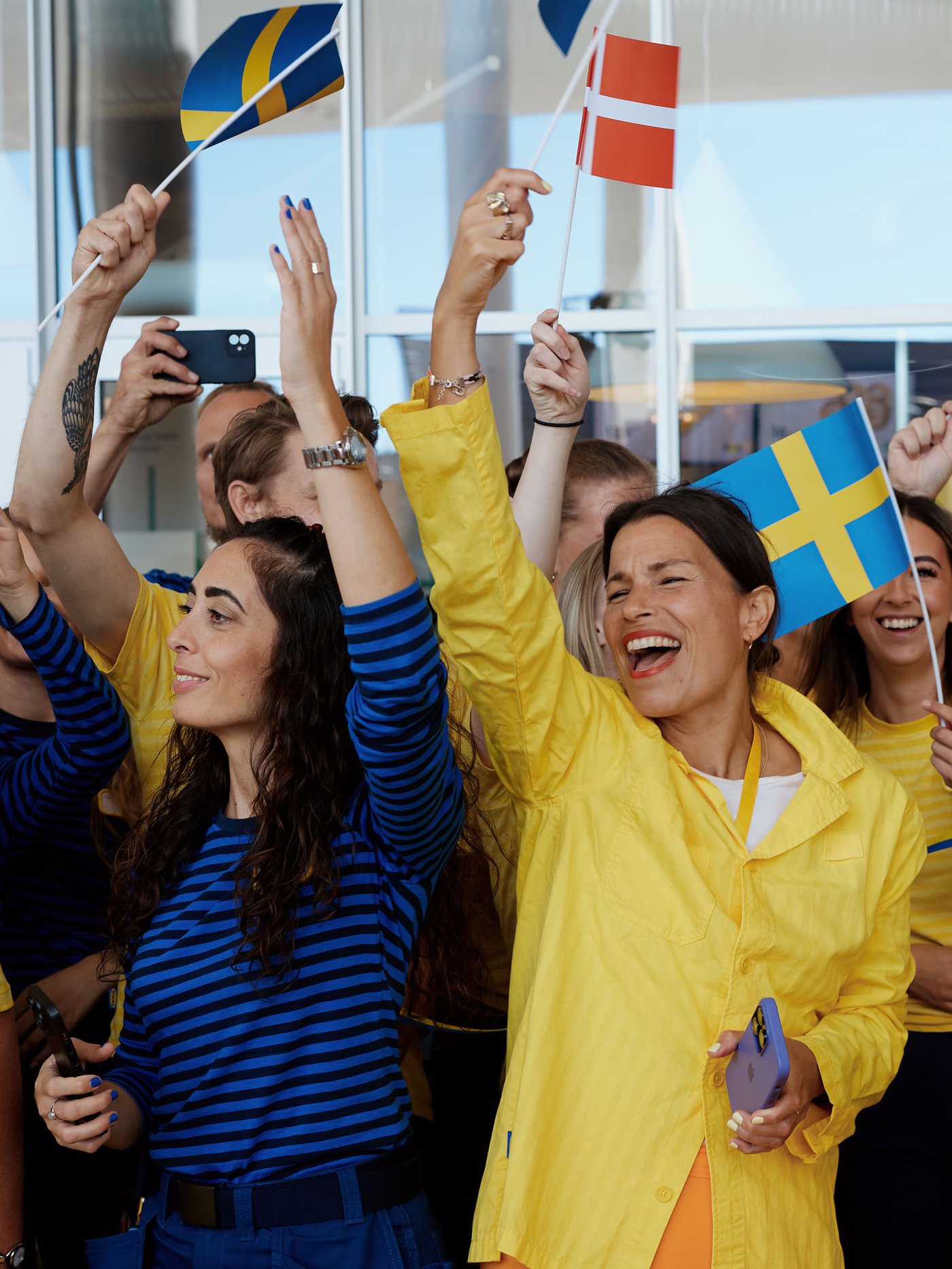 Flere glade IKEA medarbejdere står samlet og jubler og vinker mens de vifter med armene og det svenske flag.