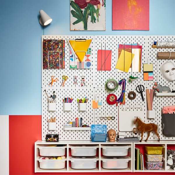 Flere hvite SKÅDIS oppbevaringstavler med tilbehør til oppbevaring av hobbysaker, montert på en vegg.