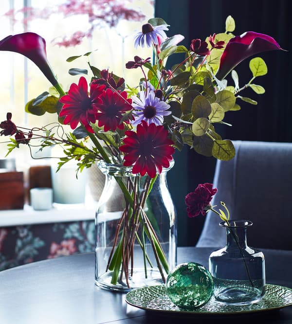 Fleurs artificielles IKEA FEJKA rouges et mauves dans un vase en verre BEGÄRLIG.