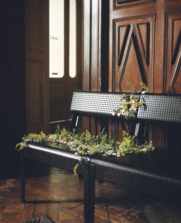 Fleurs passant dans les trous de deux chaises en métal noires.