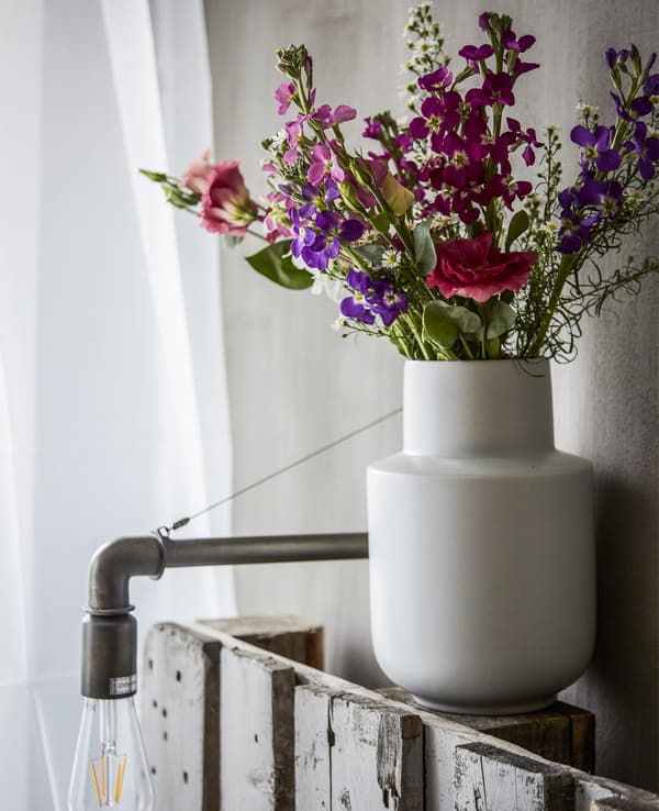Floreiro branco con flores.