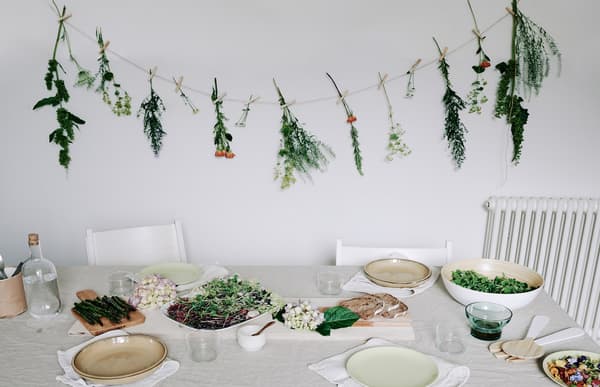 Flowers hang from string above a dining table.