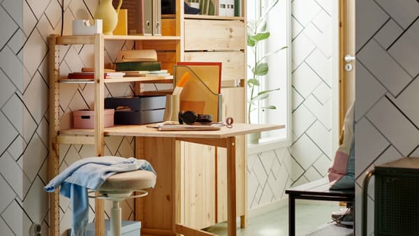 Fold-out table and shelving unit in light wood in corner of home with plant in the background