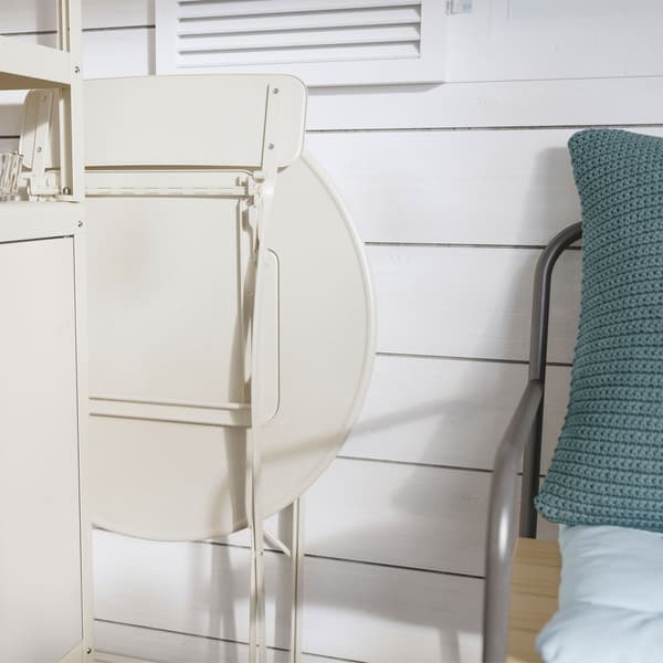 Folded IKEA SALTHOLMEN beige outdoor chair and table, leaning against a wall, near a sofa.