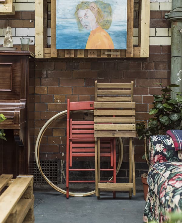 Folding chairs stacked against a tiled wall.