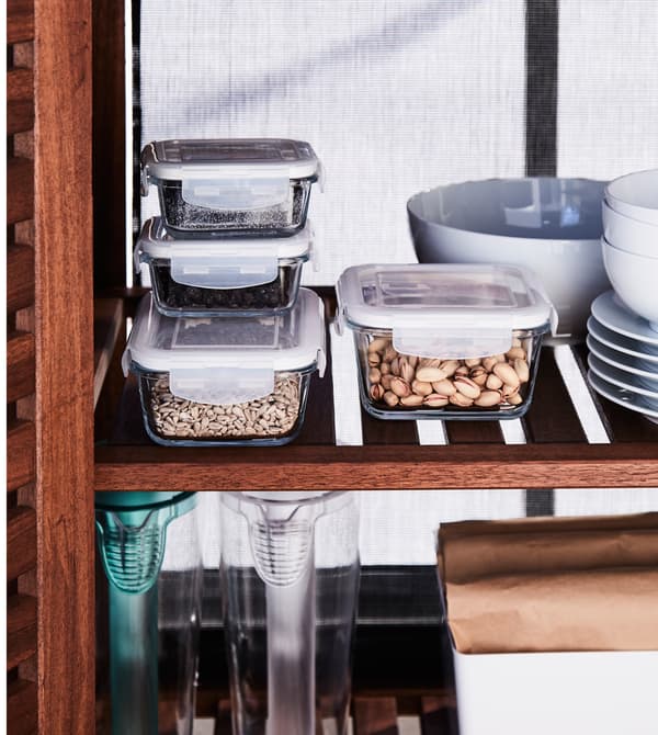 Food storage containers and tableware are stored in a closed wooden cabinet.