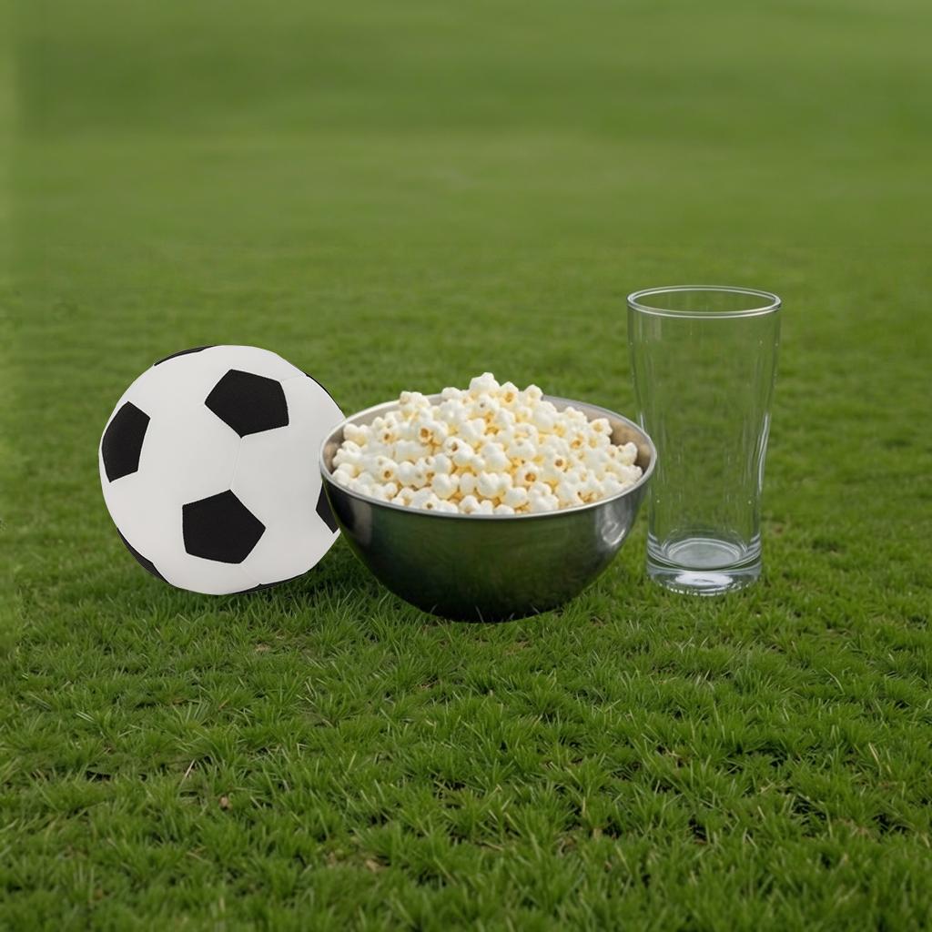 Football, a bowl of popcorn and an empty glass. Everything is on green grass.