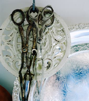 Forbici vintage appese a ganci con una decorazione in metallo.
