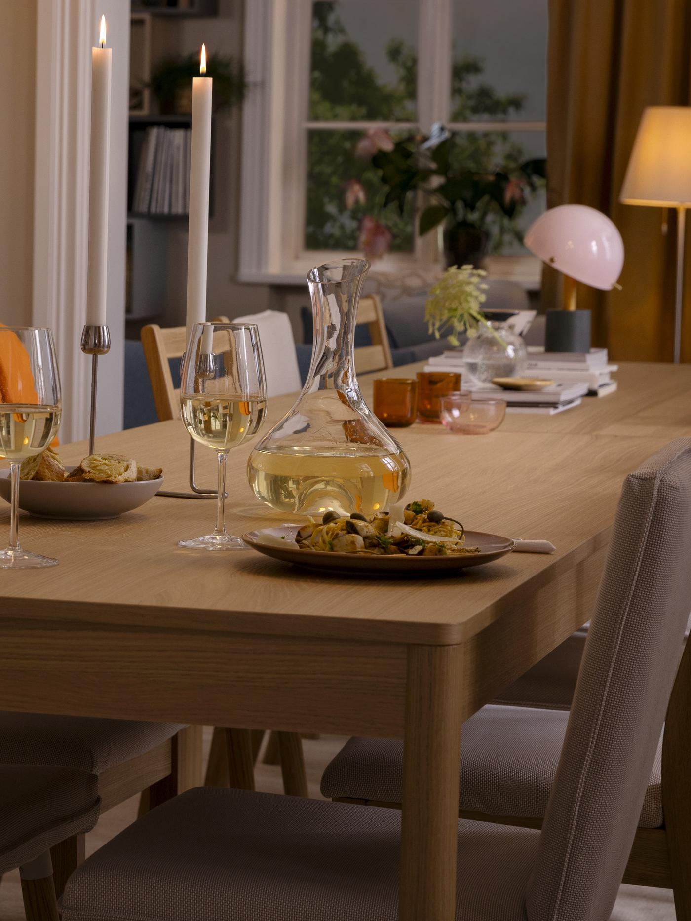 Fornirowany dębem stół TONSTAD nakryty do uroczystej okazji, z kieliszkami STORSINT, karafką STORSINT i zastawą stołową FÄRGKLAR.