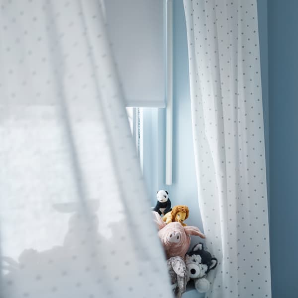 Foto av ett fönster med vita gardiner och ett gäng gosedjur som sitter i.