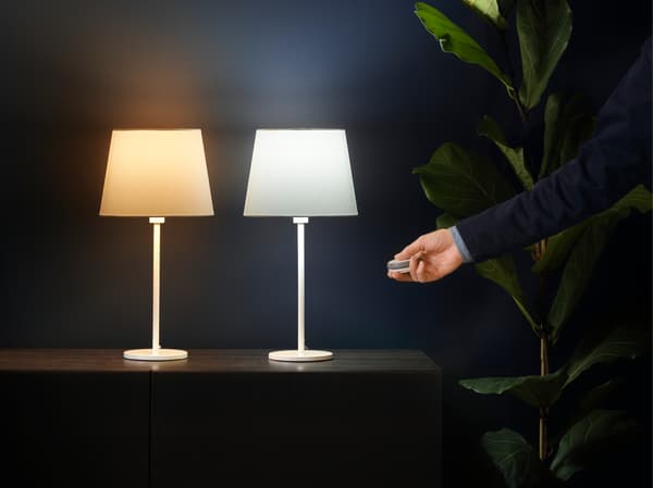 Foto av två lampskärmar samt en hand som håller i en dimmer.