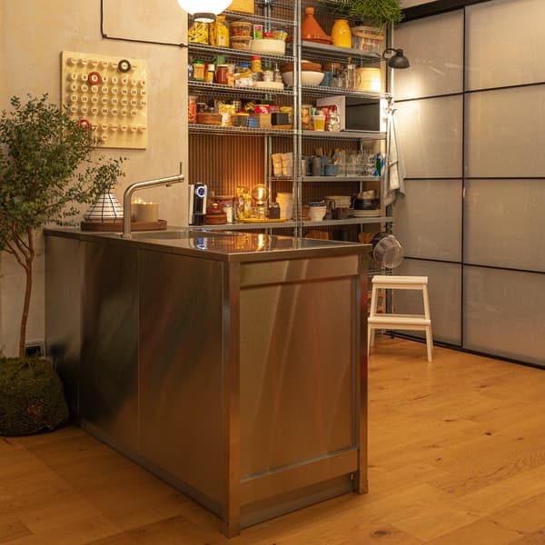 Foto panoramica dell'angolo cucina in Casa Ghali: un piano cottura ben illuminato, un lavello e sullo sfondo una dispensa ben fornita.
