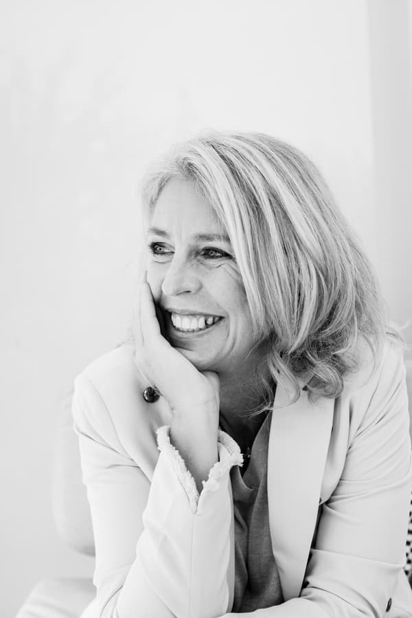 Fotografia en blanc i negre d’una dona de perfil asseguda, amb la mà a la galta i somrient.