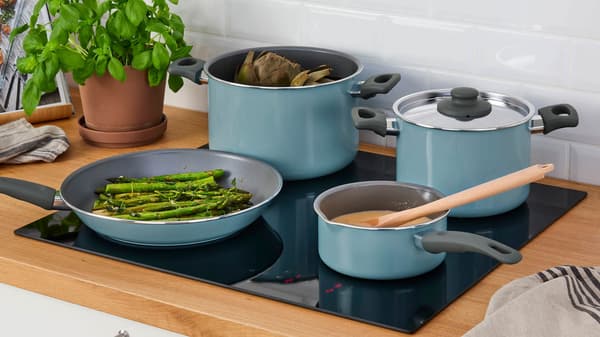 Four blue pots and pans on a black cooktop.