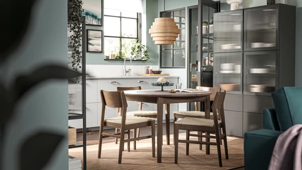 Four brown beech SKANSNÄS chairs stand at a brown beech/veneer SKANSNÄS round extendable table on a LOHALS flatwoven rug.