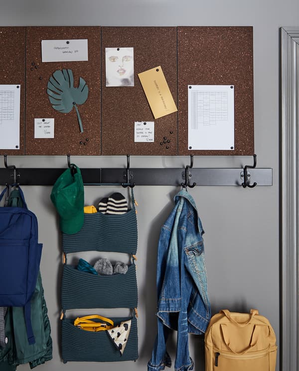 Four dark brown, wall-mounted SVENSÅS memo boards with pins with postcards, schedules and notes.