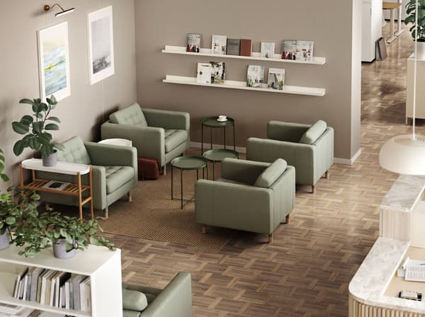 Four green LANDSKRONA armchairs with GLADOM tray tables between them. A MOSSLANDA picture ledge holds journals on the wall.
