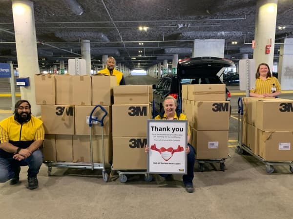 Four IKEA coworkers with boxes of N95 masks, with one holding a 'Thank you' sign.