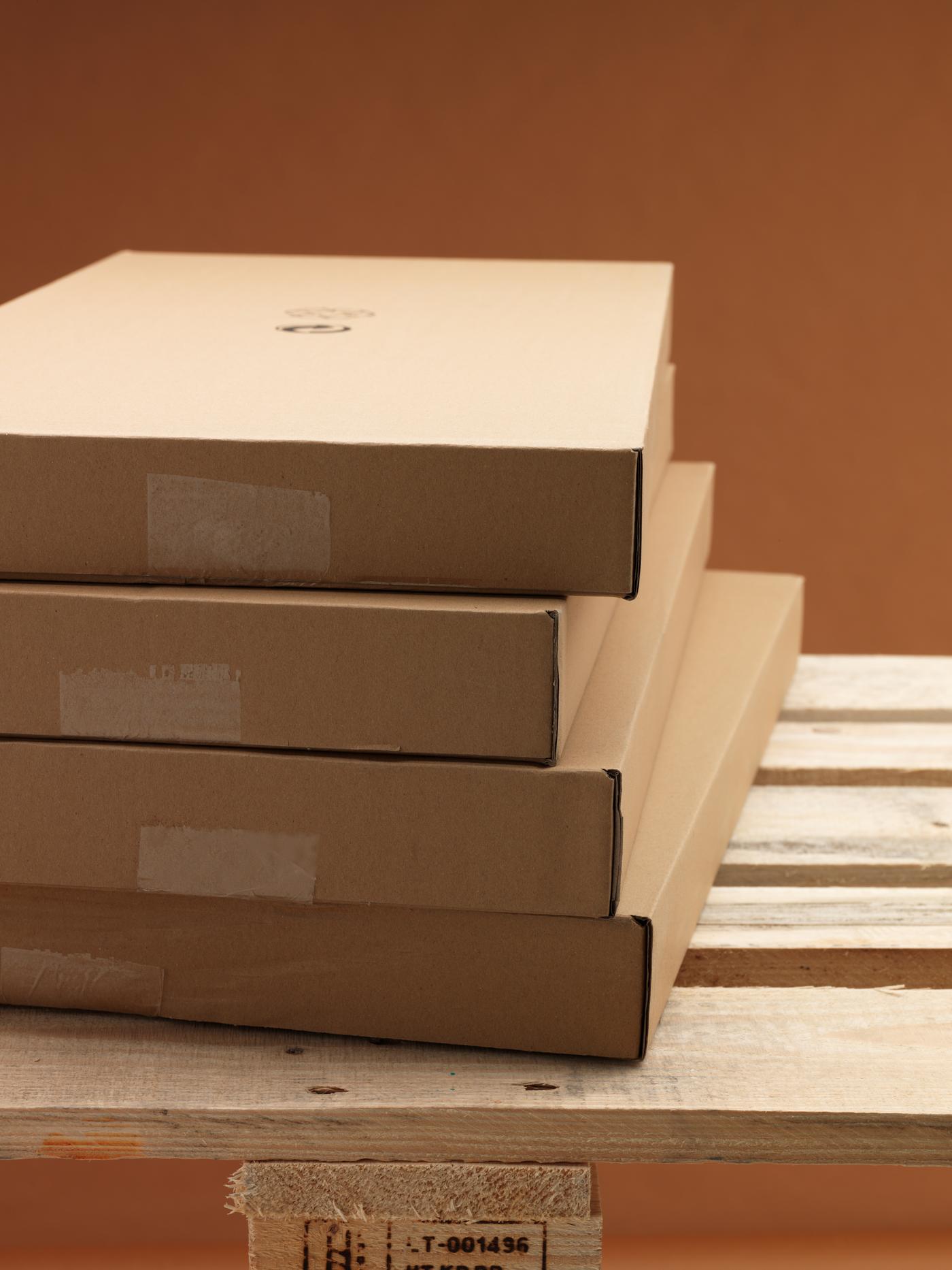 Four IKEA flat packs fashioned from recycled cardboard stacked in an orderly pile on a wooden delivery pallet.