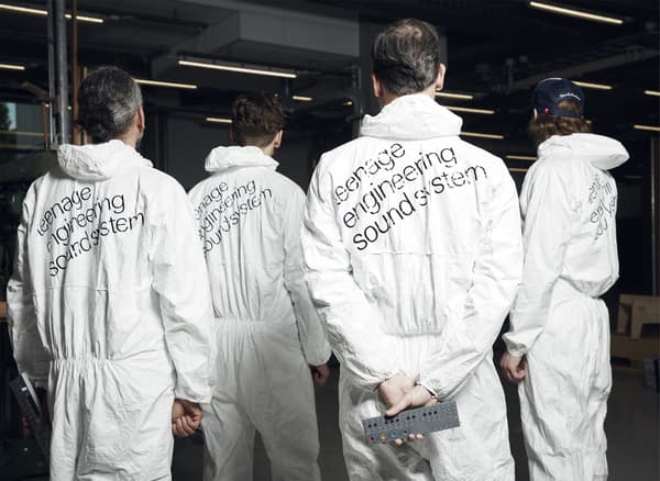 Four men wearing boiler suits with ‘teenage engineering sound system’ printed on the backs.
