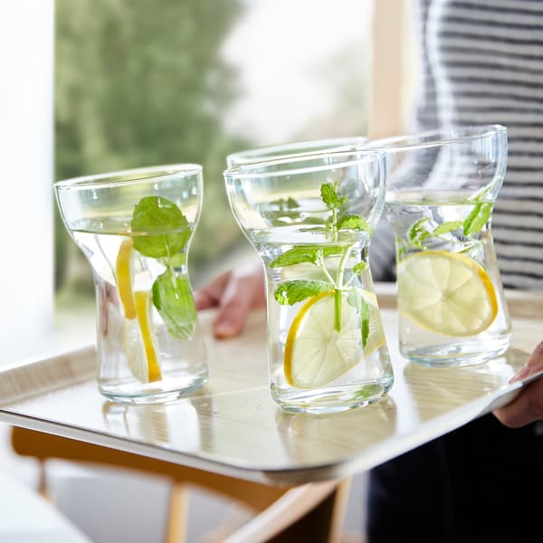 Four OMTÄNKSAM glasses on a leaning FÖRMEDLA tray. The anti-slip surface helps the glasses stand steady.