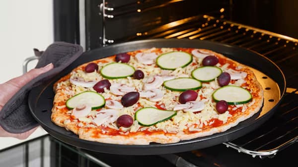 Four ouvert, avec un plat à pizza et une pizza crue