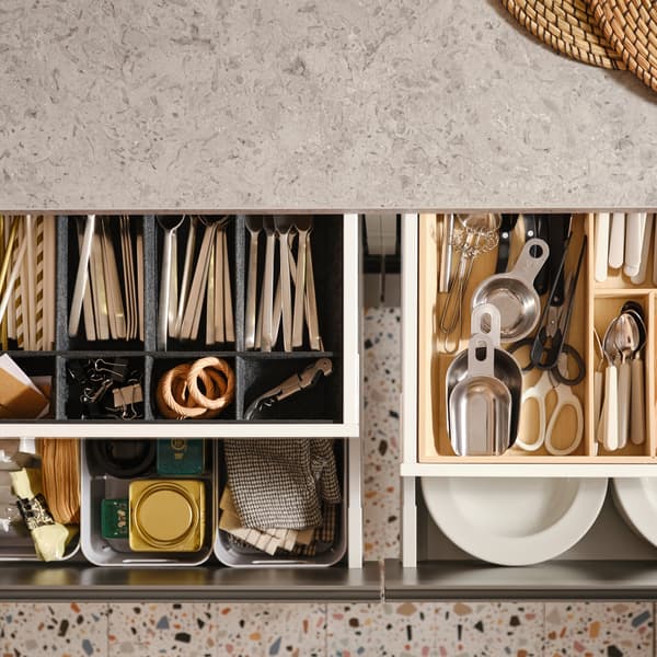 Four pulled-out MAXIMERA kitchen drawers with various items in a cutlery tray, an adjustable organiser for drawer and boxes.