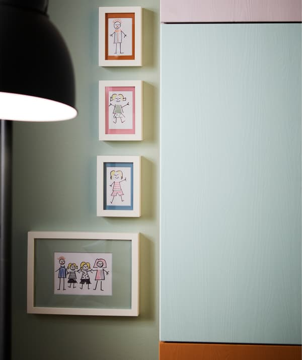 Four RIBBA picture frames with illustrations hanging on a wall, next to IVAR wall units.