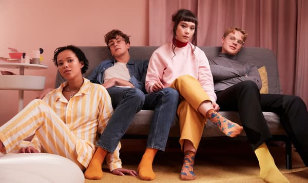 Four school friends sitting together in a sofa in a dorm room.