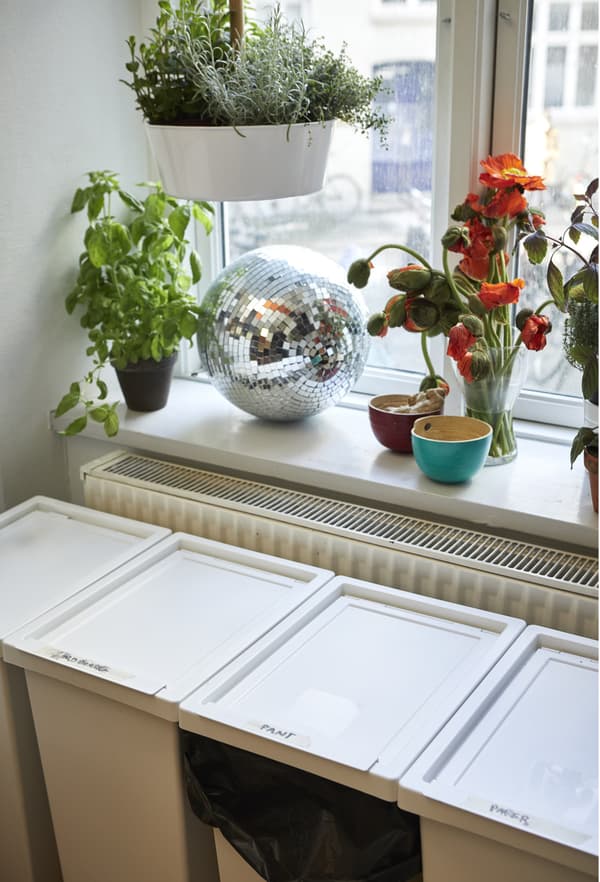 Four waste sorting bins below a windowsill in the kitchen.
