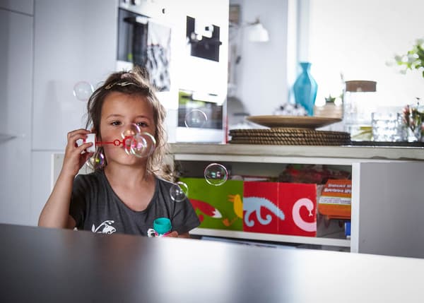 Four-year-old Helena blows bubbles by the kitchen island.