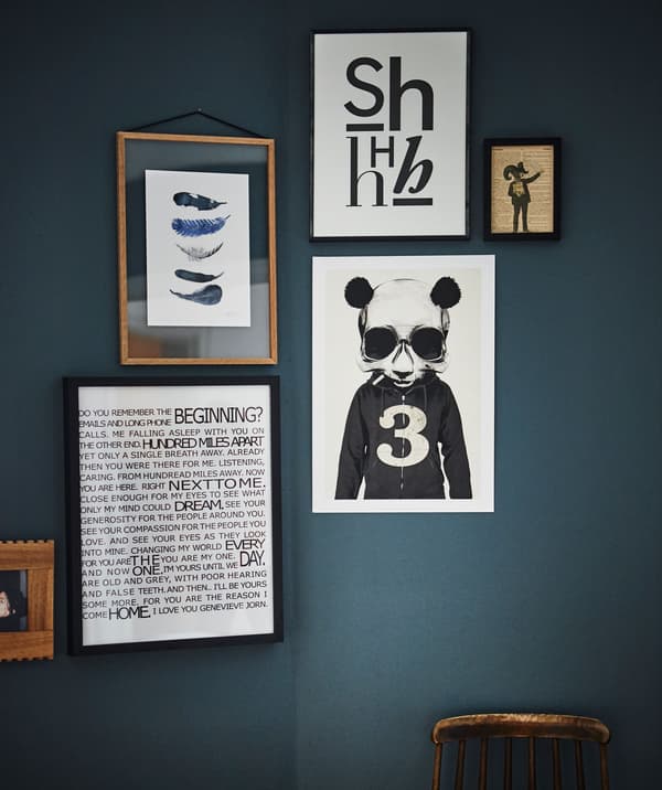 Framed graphic artwork hangs against a dark blue/green wall.
