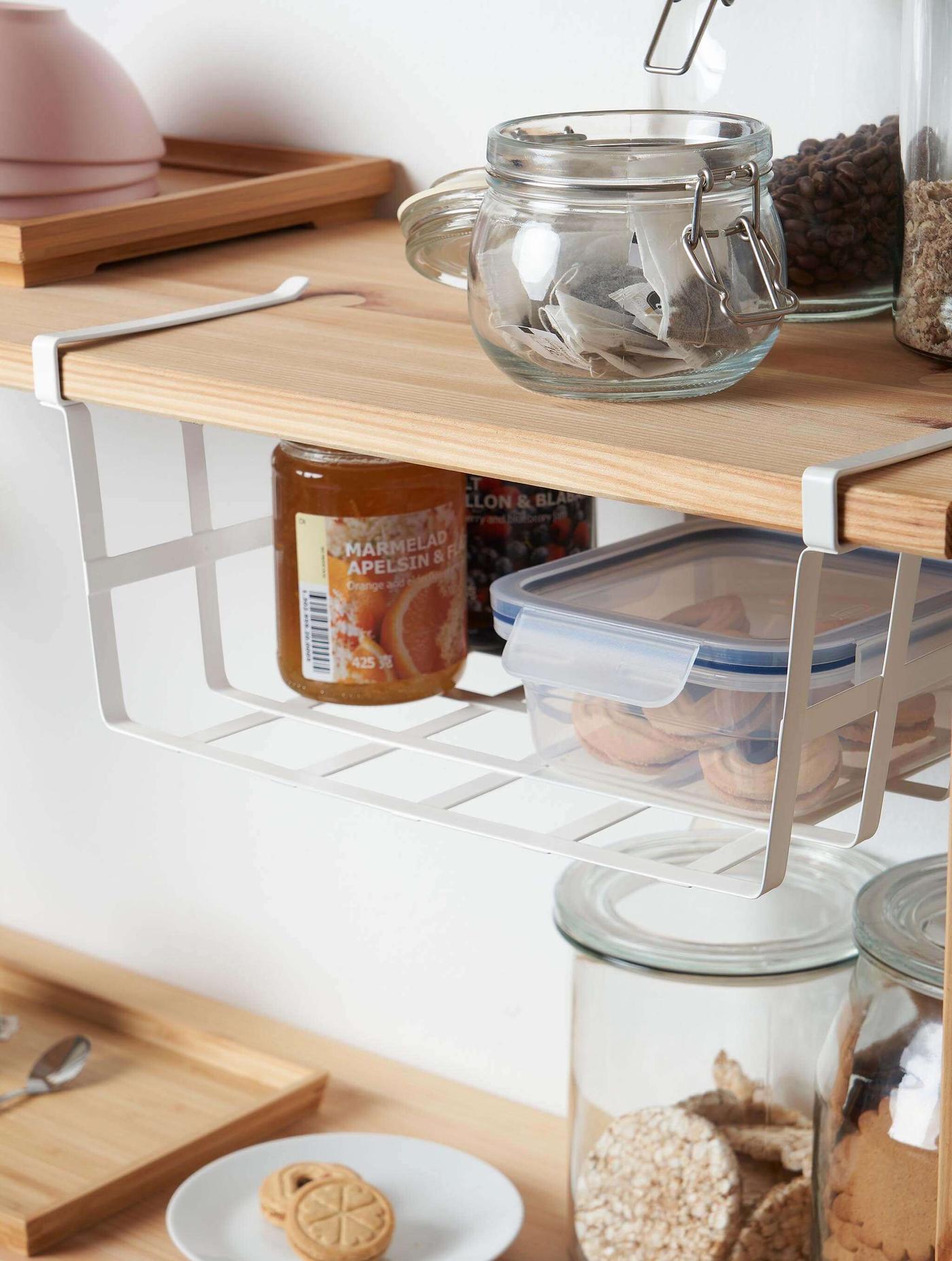Frasco de vidrio de mermelada, un recipiente de plástico y un plato de galletas en un estante.