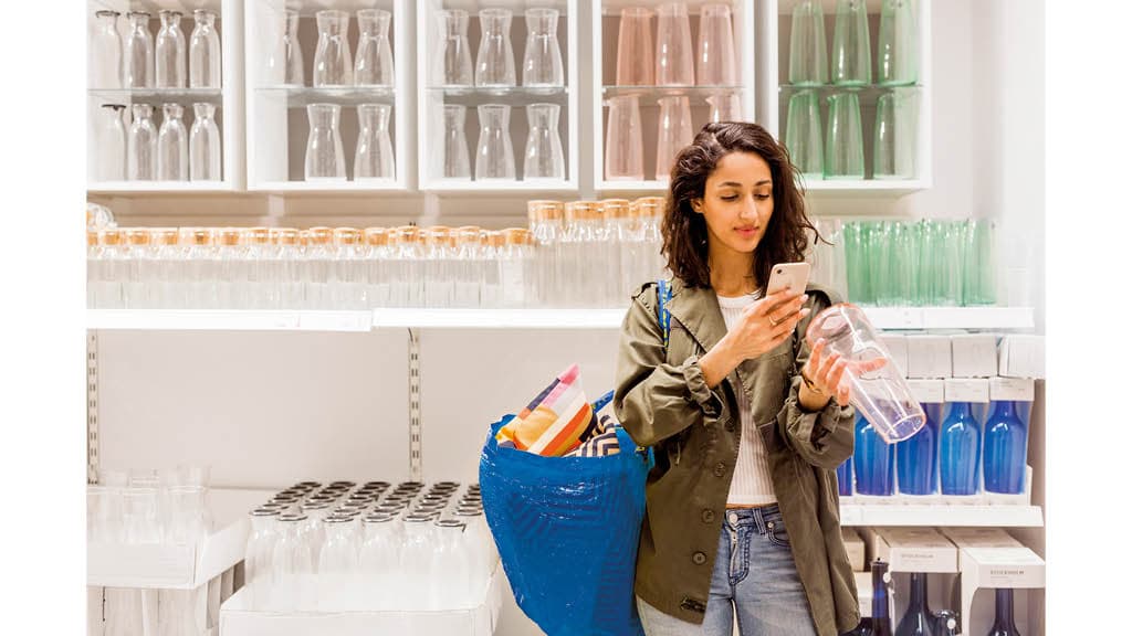 Frau benutzt ihr Telefon um bei IKEA einzkaufen