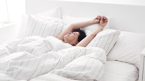 Frau erwacht gut ausgeschlafen im Bett aufgrund der richtigen Matratze 