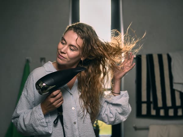 Frau föhnt sich die Haare