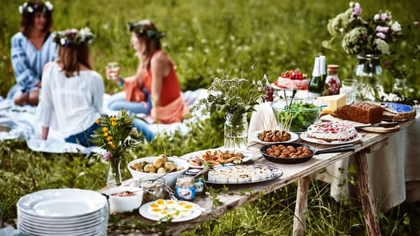 Frauen sitzen auf einer Wiese und feiern das schwedische Sommerfest Midsommar