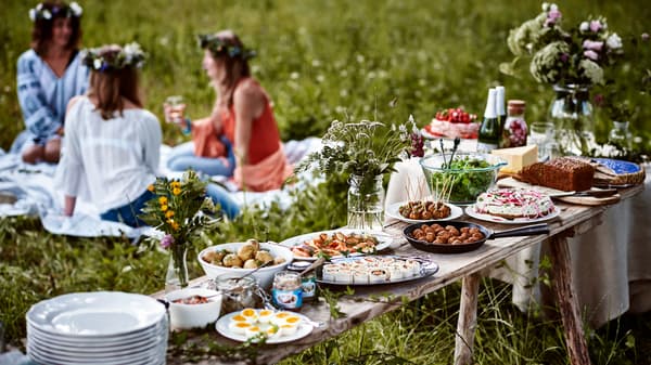 Frauen sitzen auf einer Wiese und feiern das schwedische Sommerfest Midsommar