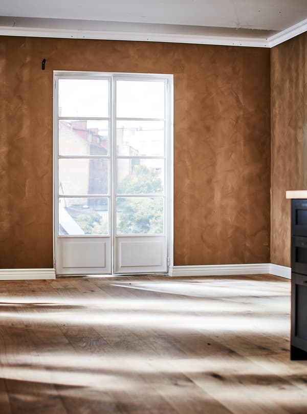 ห้องเปล่าที่มีหน้าต่างสไตล์ French, พื้นไม้ และผนังสีโทนน้ำตาลเข้มและพื้นผิวแบบหนังด้าน