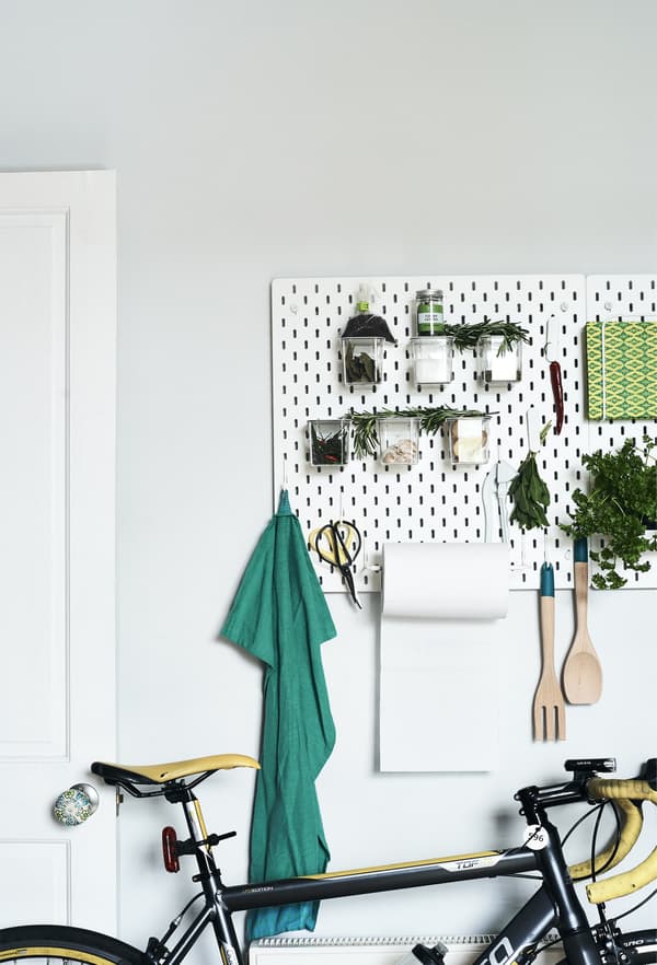 Fresh herbs and utensils stored on a pegboard.
