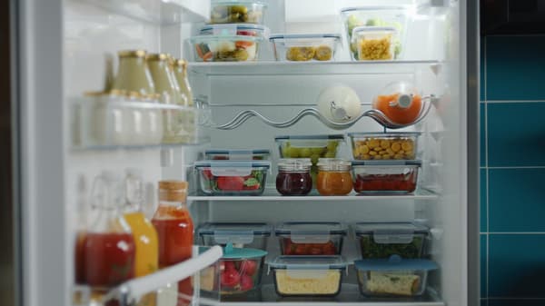 Frigorífico organizado com recipientes para alimentos e frascos de vidro.