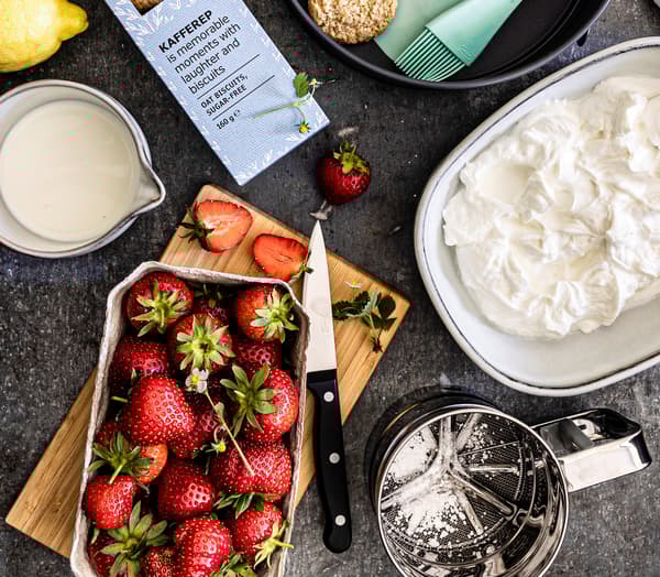 Frische Erdbeeren und Quark werden für einen Käsekuchen mit Haferkeksboden vorbereitet.