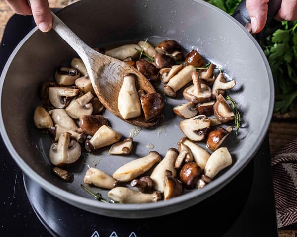 Frische Pilze werden für eine Midsommar Quiche angebraten.