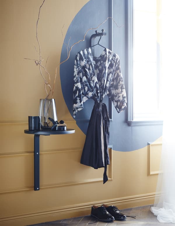 FROSTA is a round, wooden stool from IKEA that can be deconstructed and reused. This idea painted the pieces blue. The seat and a leg are now a wall-mounted table. Another leg is a wall-mounted hook with kitchen knobs attached as stoppers. 