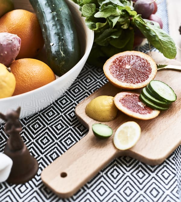 Fruits dans un saladier et fruits découpés sur une planche en bois.