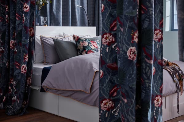 Függönyökkel körülvett ágy, sötétkék virágos mintás IKEA FILODENDRON méteráruból.