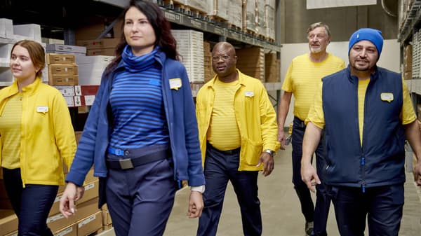 fünf IKEA Mitarbeiter die durch die Selbstbedienungshalle gehen.