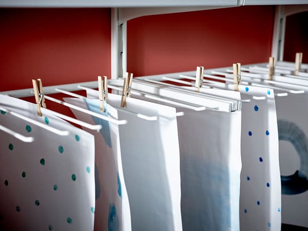 Fulls de paper acabats de pintar que pengen amb pinces en un penja-robes per a pantalons.