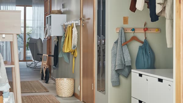 フロアにラグが敷かれ、NORDLI/ノールドリのチェストが置かれた玄関。壁面には、FLISAT/フリサットとKUBBIS/クッビスのフック付きラック、EKET/エーケト シェルフユニットが取り付けられている。
