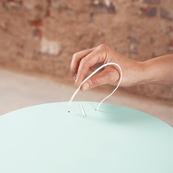 Fűzz egy vékony nejlonszálat a lyukakon keresztül, hogy kialakítsd a keresztöltést.